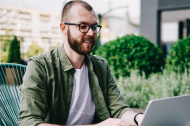 Genç hippi çocuk çevirmen tarafından internet, dil öğrenme en sevdiğim kafede yeni dizüstü bilgisayar kullanarak izlerken webinar online yolu ile modern aygıt dostum ve sosyal ağlarda takipçileri ile iletişim kurar.