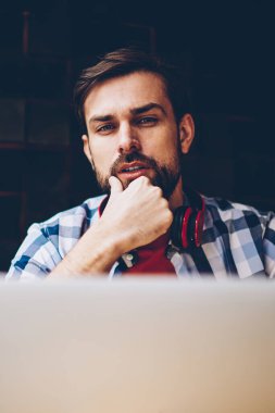 Serbest üzerinde çalışma ve dizüstü bilgisayarda kablosuz 4 g internet bağlantısı kullanarak yakışıklı sakallı hippi adam portresi. Netbook okurken kameraya bakarak boyun kulaklık ile genç adam
