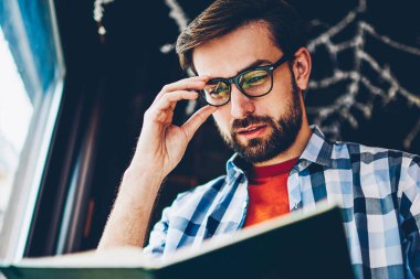 Sakal ve optik gözlük yararlı bilgiler ders için ders kitabı arama akıllı genç adamla yoğunlaşmıştır. Dalgın hipster adam okuma kitabı coworking seminerde okuyan için hazırlanıyor