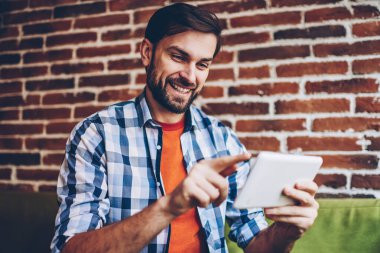 Başarılı sakallı genç adam rahat forması online sosyal ağlar üzerinden ücretsiz 4 g modern tablet sohbet metin bilgilerini yazarak giymiş Internet. Profil güncelleştirme olumlu hipster blogger