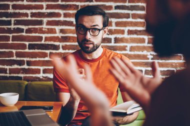 Ciddi optik gözlük alan coworking içinde toplantı sırasında arkadaşıyla tartışmaya genç adam sakallı. Birlikte laptop oturan ortak proje üzerinde meslektaşı ile strateji tartışmaya öğrenci