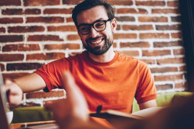 Güzel erkek tasarımcı bilgisayarda işaret ve meslektaşım coworking içinde birlikte gelişmekte olan Web sitesi çalışma hakkında iletişim sakallı. Tartışma proje sırasında gülen olumlu hipster adam