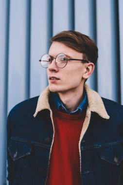 Uzak seyir vizyon düzeltme için şık gözlük yakışıklı hipster adam durulması. Düşünceli genç adam şık denim ceket ayakta açık havada kentsel ortamda giymiş. Düşünceli genç