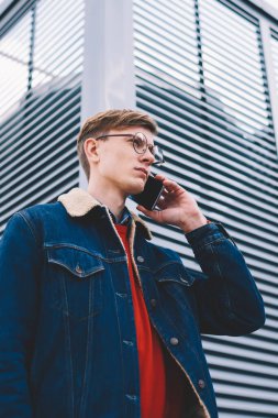 Aşağıda erkek Blogger görünümü cep telefonu sokakta geziniyor: çağrı şık kıyafeti giymiş. Ciddi hipster adam smartphone aygıt açık havada kentsel ortamda ayakta dolaşım bahsediyoruz