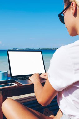 Yaratıcı kadın arkadan görünüm seyahat blogger ile güneşli gün yaz, tropikal adada uzak iş zevk millenial kadın freelancer okyanus plaj üzerinde oturan boş perde netbook yolu ile ağ