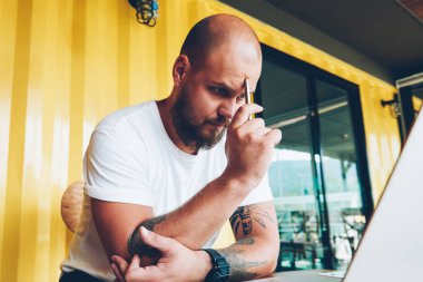 Konsantre erkek öğrenci sorun izlerken online eğitim kursları dizüstü bilgisayar, netbook, bilgi okuma projesi hakkında düşünme yetenekli erkek Tasarımcısı üzerinden sırasında çözme şaşkın