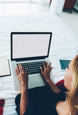 Dizüstü bilgisayarda çalışan ve rahat bir yatakta oturan serbest çalışan bir kadın klavyenin en iyi hayatı. Hippi kız evde mesai yapmak için blogda yazı yazmak için netbook kullanıyor.