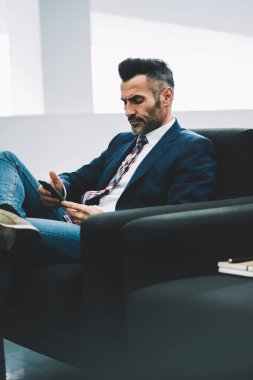 Dalgın emin işadamı bildirim koltukta oturan smartphone üzerinde okuma formal giyim giymiş. Orta yaşlı ofis çalışanı ile 4 g telefonu SMS mesaj gönderme konsantre Internet