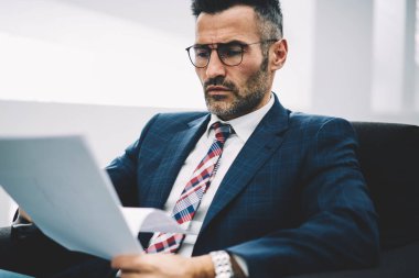 Dalgın Olgun ofis çalışanı yazılı kağıt belgeler üzerinde hesap bilgilerini analiz takım elbiseli. İşadamı 50 yaşında kurumsal şirkette çalışan mali raporları okuma konsantre