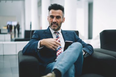 Formal giyim ofis iç dinlenme kendine güvenen olgunlaştı işadamı portresi giymiş. Akıllı gurur CEO'su 50 yaşında rahat koltukta otururken kameraya bakarak sakallı