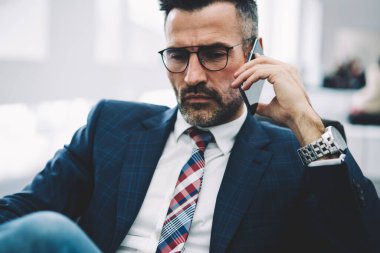 İş ortağı ile smartphone üzerinde konuşmak ve strateji telefon görüşmesi sırasında tartışırken formal giyim emin olgun girişimci. Telefon aygıtı çalışma sorunları çözme gurur CEO'su deneyimli