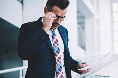 Dalgın emin icra müdürü kurumsal şirkette çalışan mali rapor okuma takım elbise giymiş. Olgun girişimci formal giyim bilgi veriyle metin belgeleri kontrol yoğunlaştı