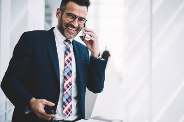 Başarılı bir iş adamı portresi smartphone aygıt üzerinde arama ve telefon konuşma ayakta Office Kurumsal şirketin kopyalama alanı alanı yakınındaki sırasında gülüyor formal giyim giyinmiş