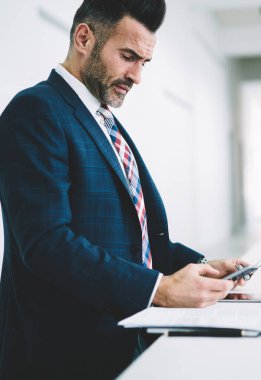 Kendine güvenen dalgın gurur CEO'su 50 yaşında gelen notifacation smartphone aygıt ayakta Office üzerinde okuma yan görünüm. Posta yolu ile 4 g cep telefonu kontrol konsantre icra müdürü internet