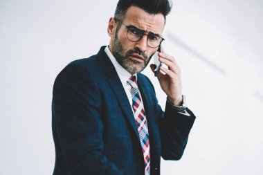 Yarım uzunluk portre emin işadamı 50 yaşında ise smartphone üzerinde konuşmak ve notlar raporlarında yapma kameraya bakıyor. Gurur CEO'su cep üzerinde çağrılırken belgelerin imzalanması deneyimli