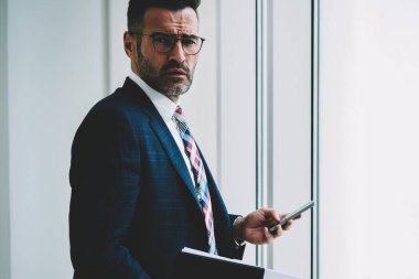 Formal giyim 4 g internet ayakta iş bilgilerinizi için tanıtım alanının yakınında bağlı smartphone aygıt üstünde posta kontrol emin olgun girişimci yarım uzunluk portre giymiş