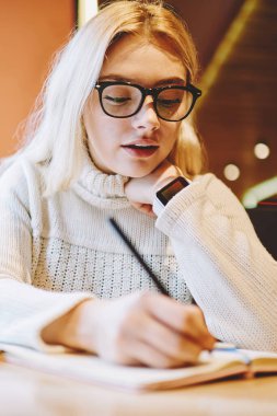 Gözlükler, kafe, yetenekli kadın serbest proje uzaktan ağ dizüstü bilgisayarı üzerinde çalışma tamamlamak için planlama yapma dizüstü bilgisayar ile oturup Not Defteri'nde ödev görev yazma zeki kız öğrenci