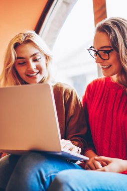 İnternet mağazasından alışveriş yapan hippi kızlar birlikte kafede dinleniyorlar, gülümseyen kız öğrenciler video izliyorlar ve birbirleriyle sohbet ediyorlar birlikte çalışma alanlarında online dersler öğreniyorlar.