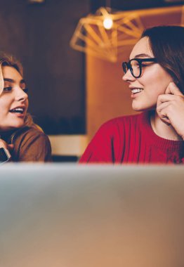 Ödev ödevi sırasında iletişim kuran gülümseyen hipster kızları fikirlerini paylaşıyorlar, kadın en iyi arkadaşlar birlikte çalışma odasında sınav hazırlığı hakkında konuşuyorlar.