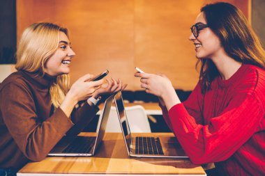 Neşeli genç kadınlar başarılı serbest proje hakkında harika bir haber okuyan ve birlikte ortak proje hazırlama birbirinizle konuşmak smailing hipster kızlar birbirleriyle iletişim kurmak