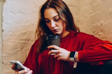 Dalgın genç kadın Smartphone cep telefonu ile ödeme, düşünceli hippi kız alan coworking içinde kahve ile dinlenme süre sosyal ağlar üzerinde cep telefonu içeriği güncelleştirmek için makbuz almak posta kontrol