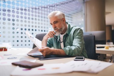 60 'lı yaşlarda olgun bir profesyoneldi. Ofisteki iş raporlarını analiz ediyordu. Büyük pencerelerden geçen doğal ışık, günlük kıyafetler, elinde gözlük. Kıdemli iş gücü kavramı, verimlilik, odaklanma