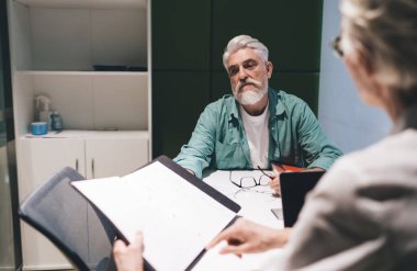 Modern ofiste yenilikçi proje fikirlerini tartışan deneyimli profesyoneller. Kıdemli iş kadını iş arkadaşlarına stratejik belgeler sunuyor, takım çalışması, yaratıcılık, iş yerinde etkili iletişim