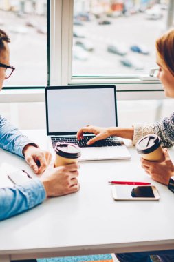 Arkadan görünüşü ve erkek öğrenci dizüstü bilgisayar ekranı, sahte hakkında bilgi alan coworking içinde işbirliği sırasında fikirleri tartışmak meslektaşları gözatmak için kullanarak ortak proje için araştırma yapma