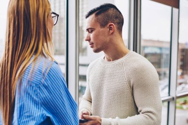 Kadın ve erkek meslektaşlarım, fikir paylaşımı çalışma projesinin yapımı çözümler iletişim sırasında dostça sohbet cowokers ayakta modern iç ofis penceresinde yakınındaki kırmak