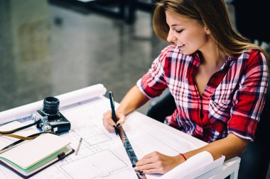 Gülümseyen kız öğrencinin Üniversitede kampüs, mutlu kadın mimar inşaat hazırlanması planı üzerinde çalışmanın tamamlanması ile memnun ileti örneği ile kroki çizim yaratıcı görev yapmanın tadını çıkarıyor