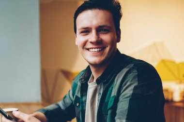 Kahve molası mutlu adam kamera cep telefonu ağ için iyi kablosuz bağlantı ile memnun gülümsüyor seyir telefon yoluyla sohbet keyfini rahat kıyafet neşeli hipster adam portresi