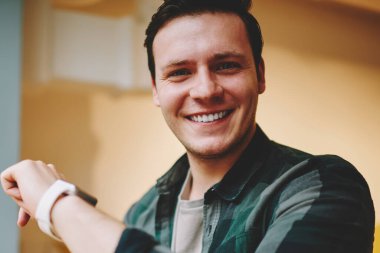 Bilek yararlı uygulamalar, mutlu erkek öğrenci kameraya seyir smartwatch özellikleriyle heyecan ile taşınabilir bilgisayarda modern dijital gadget giyen neşeli hipster adam portresi memnun