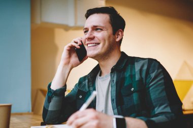 Not defterinde yazılı ve de coworking alanı, kredi hakkında danışmanlık sırasında bilgi notları memnun hizmet bankacılık yapma mutlu genç adam oturmuş telefonda konuşurken neşeli hipster adam