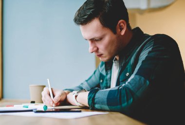 Çalışan işlemi, ödev görevleri yerine getirmeye ve notlar bilgi üniversite sınavlarına hazırlık akıllı hipster adam yaratıcı erkek tasarımcı çizim kroki kafe iç oturan konsantre