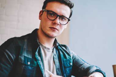 Gözlük vizyon düzeltme mesafe iş sürecinde, profesyonel erkek serbest kamera Cafe bakarak yayın makaleleri notlar yapmak için ciddi hipster adam portresi
