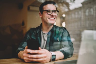 Smartphone için ağ oturma kafe iç ile teknoloji, kahve dükkanı iyi wifi ile uzaktan çalışma müreffeh erkek freelancer memnun kullanarak gözlük mutlu genç adam