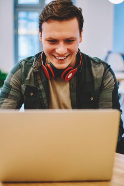 Online Oyunlar serbest zaman sırasında netbook üzerinde film izlerken gülen mutlu genç adam iyi kablosuz bağlantı Office'le coworking içinde dizüstü bilgisayar oynarken zevk heyecan hipster adam