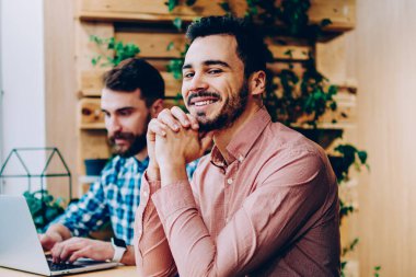 Üniversite kampüsünde başarılı freelancer online başlamak ile arkadaşı ile memnun dizüstü bilgisayarda ödev erkek arkadaşıyla oturan kamera bakarak gülümseyen yakışıklı hipster adam portresi