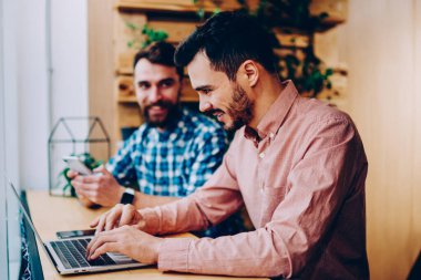 Yetenekli bir erkek. Dizüstü bilgisayarla uzak mesafelere odaklanmış. Çalışma alanında meslektaşlarıyla oturuyor.