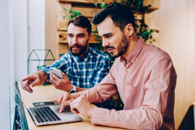 İki erkek meslektaşları üzerinde işbirliği geliştirme projesi uygulaması dizüstü bilgisayar, netbook monitör ofis coworking oturan bilgi hakkında arkadaşıyla danışmanlık işaret hipster adam üzerinde kontrol
