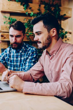 Konsantre erkek birlikte dizüstü üzerinden proje üzerinde işbirliği karar geliştiriciler hesaplamak, ev ödevi görevi kampus içinde netbook üzerinde araştırma yapmak için fikirler tartışırken ciddi hipster çocuklar BT