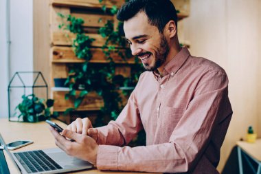 Neşeli hipster adam komik video gülüyor Smartphone'da serbest zaman sırasında genç erkek müreffeh freelancer telefon online kazanç para hareket bildirim almak ile memnun izledim