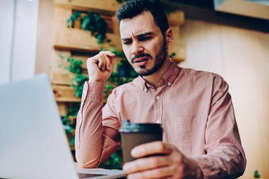 Uzaktan, kızgın genç erkek dizüstü ve üzgün faturaları internet bağlantısı kullanmak için almak posta kontrol çalışma netbook üzerinde dosyaları karşıdan yüklerken hipster adam yazılım hataları ile rahatsız vurguladı