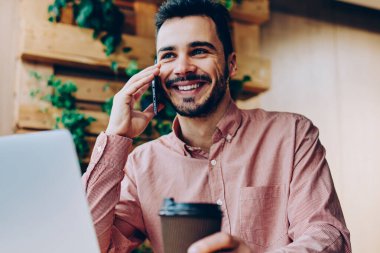 İş yerinde bilgisayarla uzaktan telefon görüşmesi yapan başarılı genç, serbest çalışan yakışıklı, gülümseyen hippi kahve molasında cep telefonu sohbetinden zevk alıyor.