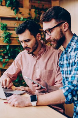 Profesyonel geliştiriciler dizüstü bilgisayarda güncelleme yazılımları birlikte çalışabilirliği kontrol ediyorlar, genç hipster gençler internet sayfasından bilgi okuyor ve internet üzerinden rezervasyon yapıyorlar.