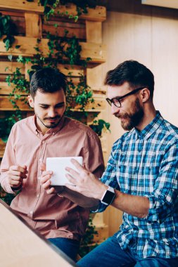 Genç hipsterlar yeni taşınabilir bilgisayarları ve ara verildiğinde ortak çalışma alanı içinde iletişim kuran uygulamaları kontrol ediyorlar, yetenekli geliştiriciler dijital tablet üzerindeki yazılımı güncellemekten memnun kalarak teknolojiyle ilgili fikirleri tartışıyorlar.