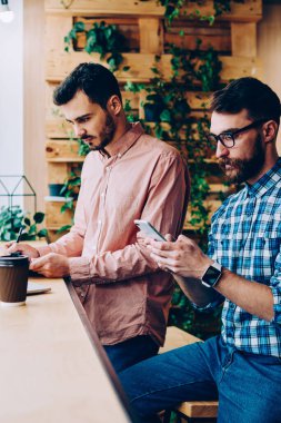 Genç yetenekli erkek bu bilgi için programlama dizüstü bilgisayar ve akıllı telefon üzerinden kontrol üzerinde çalışan geliştiriciler, hipster adam arama numarasına meslektaşı ise cep telefonu üzerinde Web'den Haberler