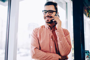 Cep pencere duran, Genç adam tarifeler telefon cep telefonu konuşma bir arkadaşım olması için memnun gülümseyerek telefonu konuşurken rahat kıyafet neşeli hipster adam portresi