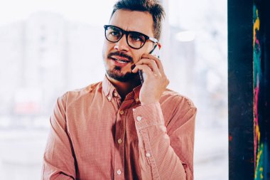 Erkek işadamı cep telefonu operatörüyle konuşurken hoşnutsuz bir yüz ifadesi takınıyor, genç hippi müşteri destek hattını beklemekten rahatsız oluyor, sorunu çözmek için çağrı yapıyor.