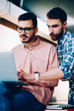 Yetenekli erkek öğretmen, okulda öğrencilere programlama araçlarını anlatıyor. Hipster çocuk, arkadaşa bilgisayardaki yazılımı güncellemesi için yardım ediyor.